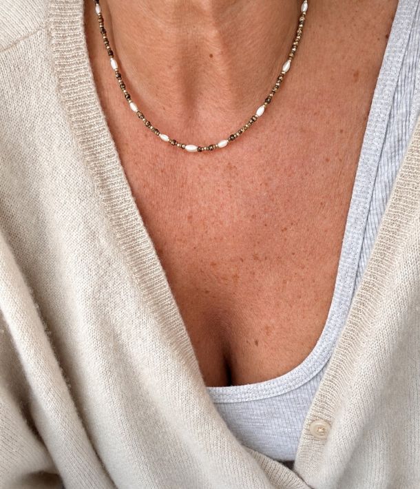 Collier Nikki 32 Collier Suzie en perles Miyuki léopard et dorées, avec perles de nacre, porté sur la peau avec un gilet écru – Loumaé Bijoux.