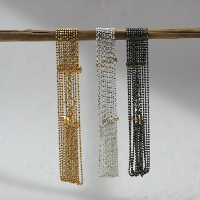 Bracelet manchette composé de 10 chaînes fines, effet fluide et “dansant”, en or laminé, argent 925 ou argent 925 rhodié noir, délicat et lumineux sur fond blanc.