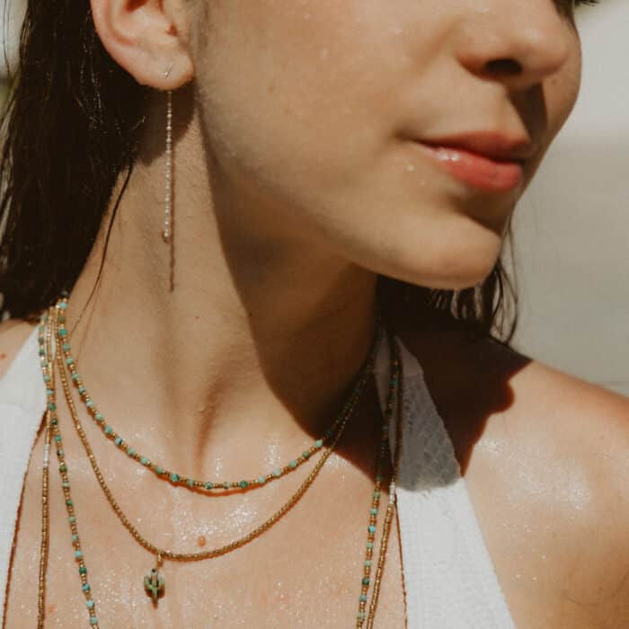 Collier ras de cou LOVA en hématite dorée et pierres naturelles blanches porté sur peau