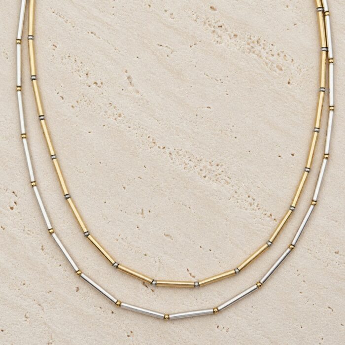 Collier Nova Loumaé Bijoux en deux versions bicolores, tubes en or laminé et argent 925, sur travertin clair.
