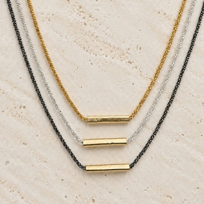 Collier Lison Loumaé Bijoux en trois finitions : doré, argent 925 et argent rhodié noir, sur travertin clair.