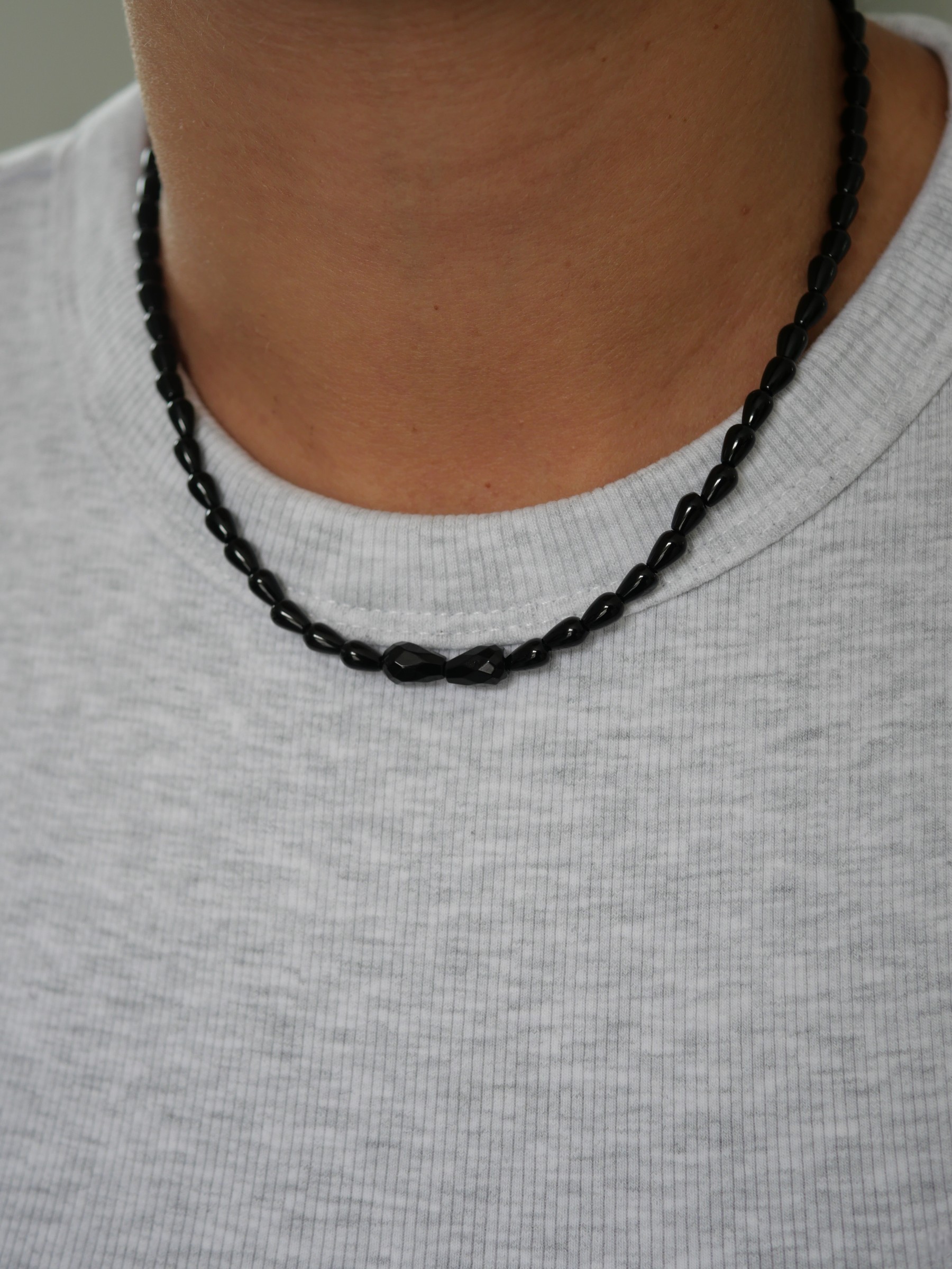 Collier Sweet rebel 2 Collier Sweet Rebel en onyx noir porté sur un tee-shirt gris clair, avec perles allongées et deux pierres centrales facettées.