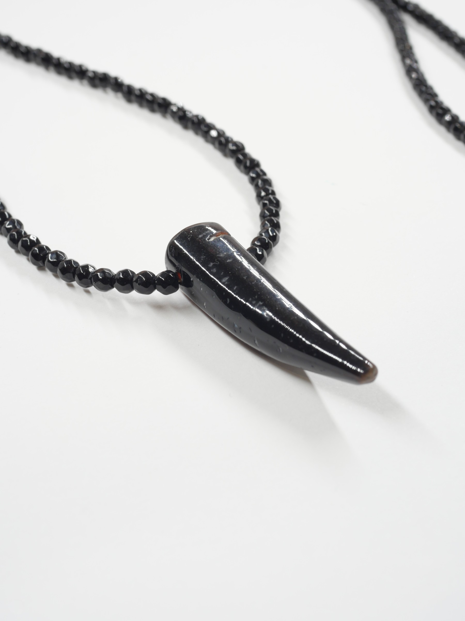 Sautoir Wild love 4 Gros plan du pendentif corne en agate et des perles d’onyx noir facettées du sautoir Wild Love de Loumaé Bijoux.