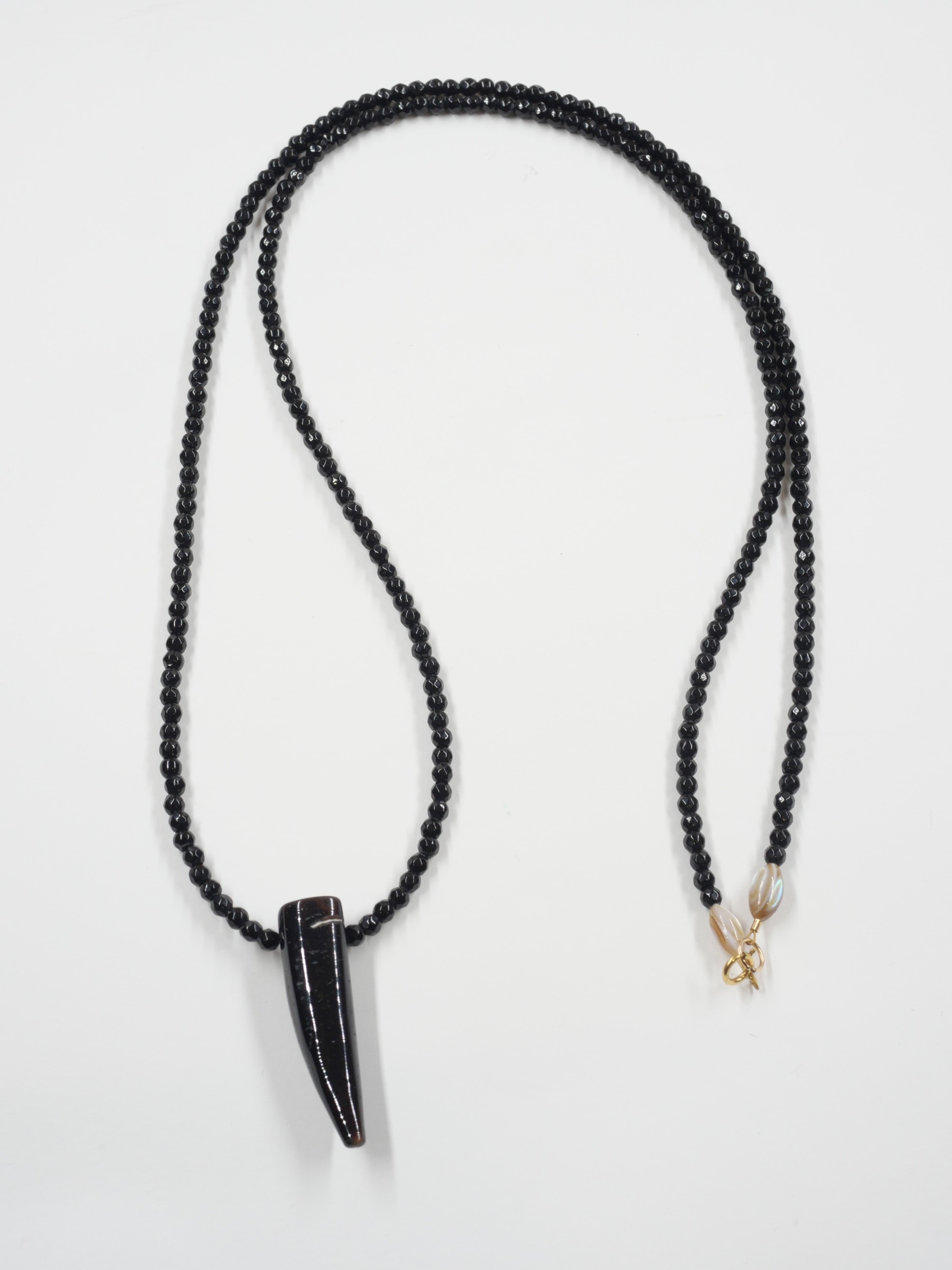 Sautoir Wild love 3 Sautoir Wild Love en onyx noir avec pendentif corne en agate, perles de nacre et fermoir en or laminé, présenté à plat sur fond blanc.