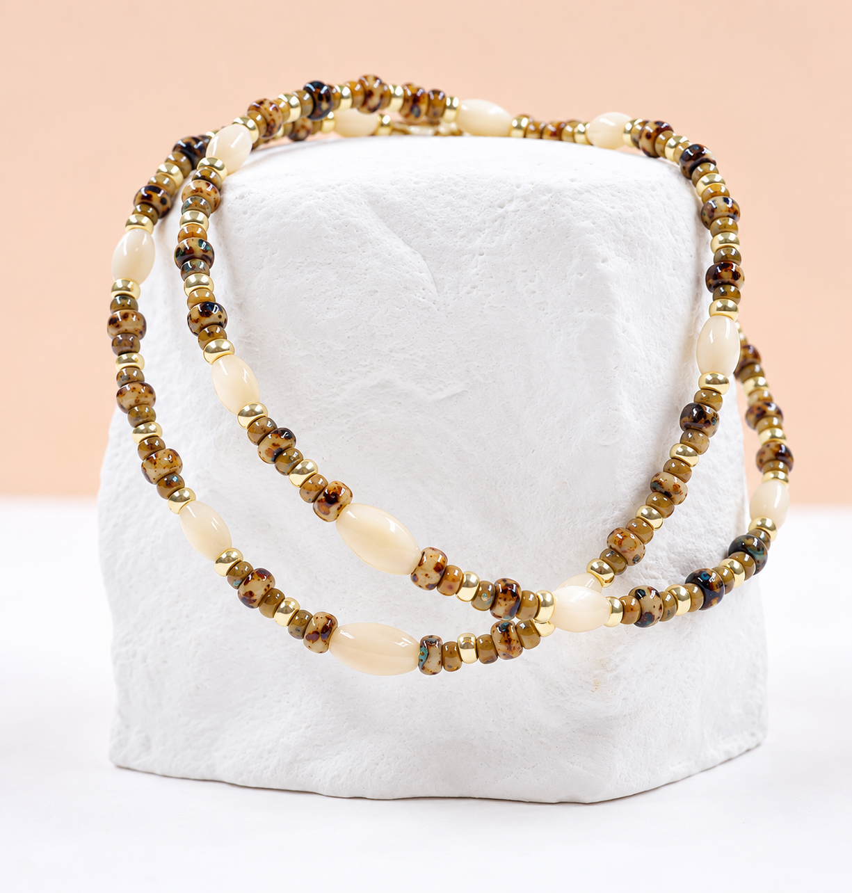 Bracelet Suzie 1 Bracelet Suzie en perles Miyuki japonaises aux motifs léopard et dorés, avec perles de nacre en forme d'olive, présentés sur un support blanc – Loumaé Bijoux.