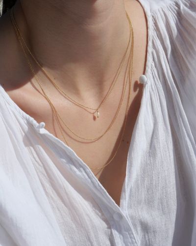 Collier Elsa rhodié noir 13 Collier Maggie triple rang en argent 925 plaqué or 3 microns, composé de trois chaînes fines de longueurs différentes. Bijou minimaliste et élégant porté sur une blouse blanche, fabrication française.