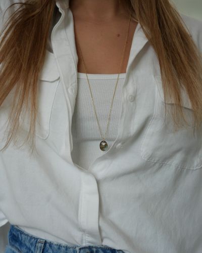 Sautoir Misty en argent 925 plaqué or 3 microns, avec pendentif ovale en labradorite aux reflets bleu-vert, porté sur une chemise blanche.