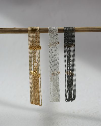 Bracelet manchette composé de 10 chaînes fines, effet fluide et “dansant”, en or laminé, argent 925 ou argent 925 rhodié noir, délicat et lumineux sur fond blanc.