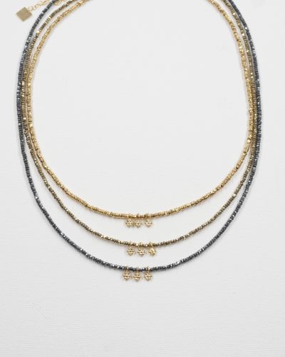 Trois colliers ras de cou Séléna en hématite facettée dorée, kaki et grise, chacun orné de trois petites fleurs dorées, présentés sur fond blanc.