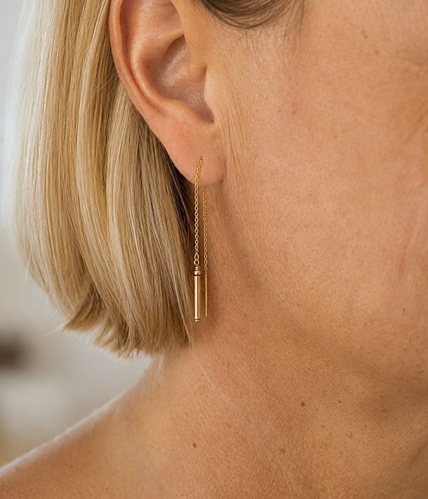 Collier Alba 11 Boucle d’oreille Nova en or laminé avec chaîne traversante et tube fin, portée à l’oreille.