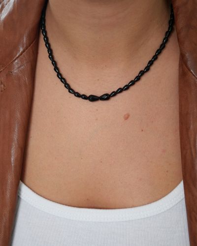 Collier Sweet Rebel en onyx noir porté avec un débardeur blanc et une veste en cuir marron, détail des deux pierres centrales facettées.
