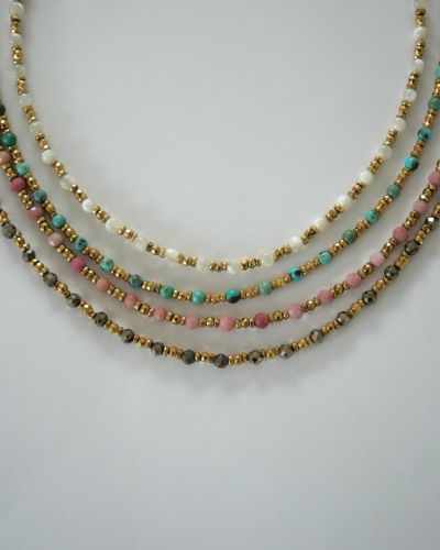 Collier ras de cou LOVA en hématite dorée et pierres naturelles blanches porté sur peau