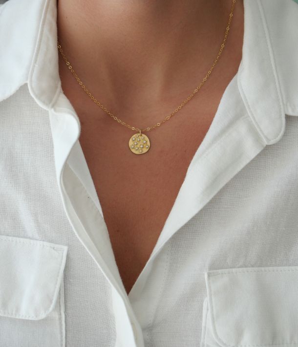 Collier Céleste porté avec une chemise blanche, chaîne fine en gold filled et médaille étoilée bicolore.
