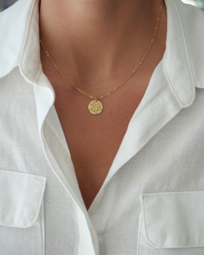 Collier Céleste porté avec une chemise blanche, chaîne fine en gold filled et médaille étoilée bicolore.