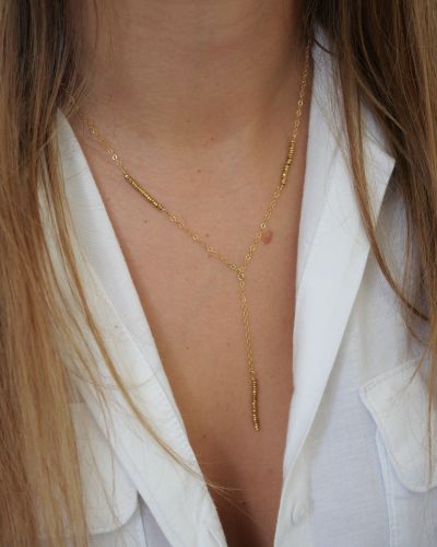 Collier Jane en or laminé et hématite dorée, porté sur la peau avec une chemise blanche ouverte.