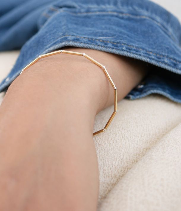 Collier Alba 12 Bracelet Nova en tubes d’or laminé et petites perles en argent 925 porté au poignet avec une chemise en jean.
