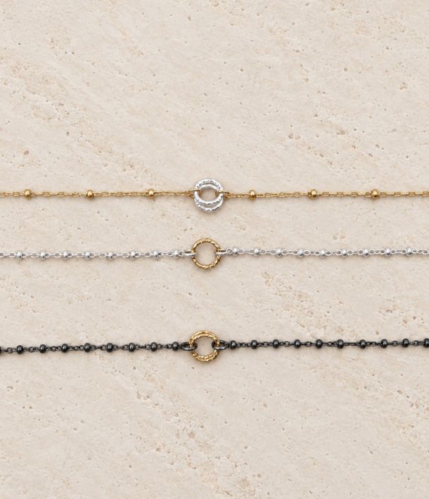 Trois bracelets Naty bicolores en or laminé, argent 925 recyclé et argent 925 recyclé rhodié noir sur travertin clair