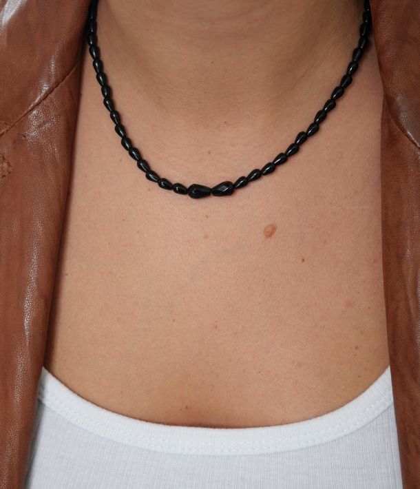 Collier Sweet Rebel en onyx noir porté avec un débardeur blanc et une veste en cuir marron, détail des deux pierres centrales facettées.